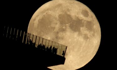 People standing on the Edge NYC watch a full hunter's moon rising in New York in October 2021.
